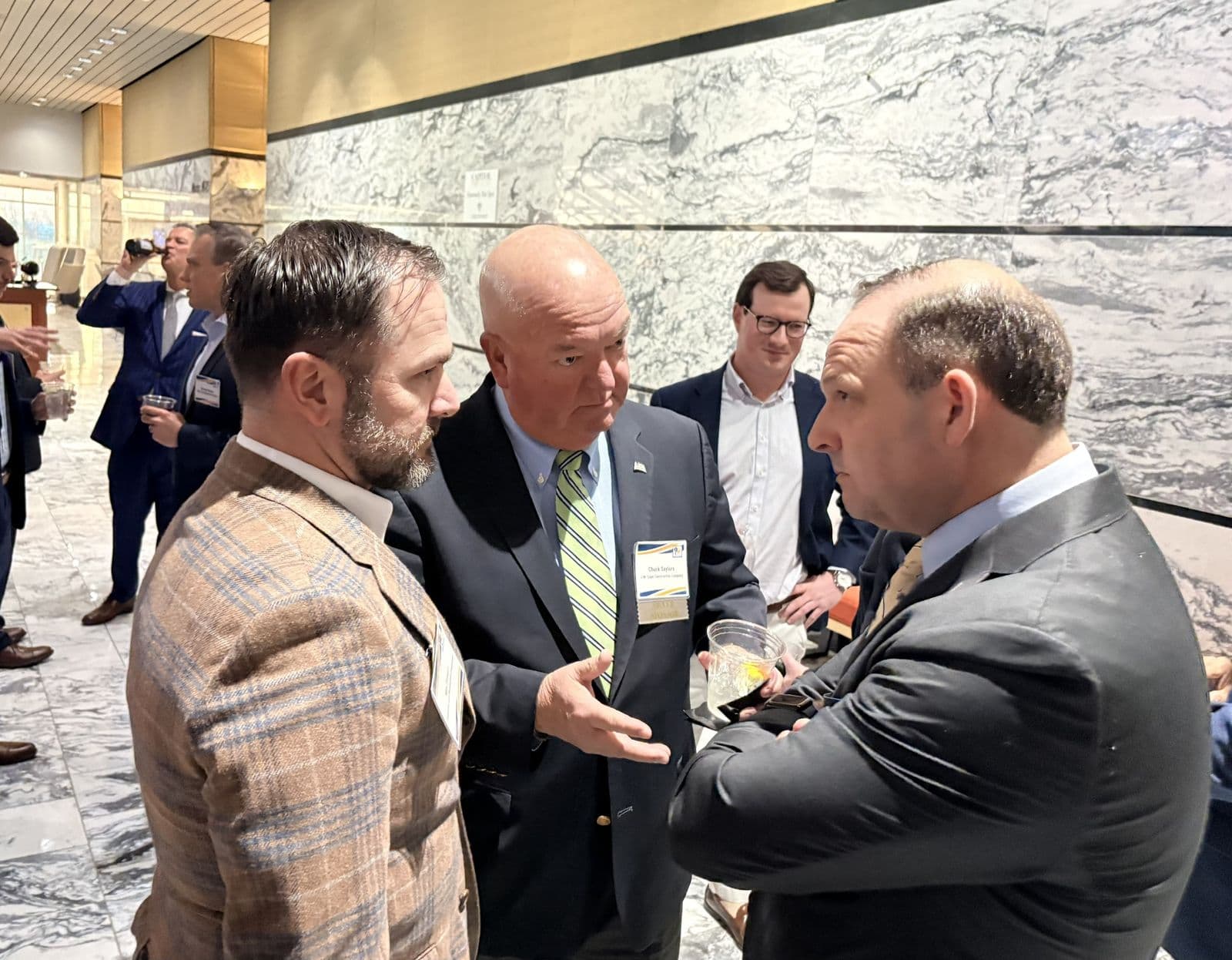 Conversation in a marble corridor during a legislative event.
