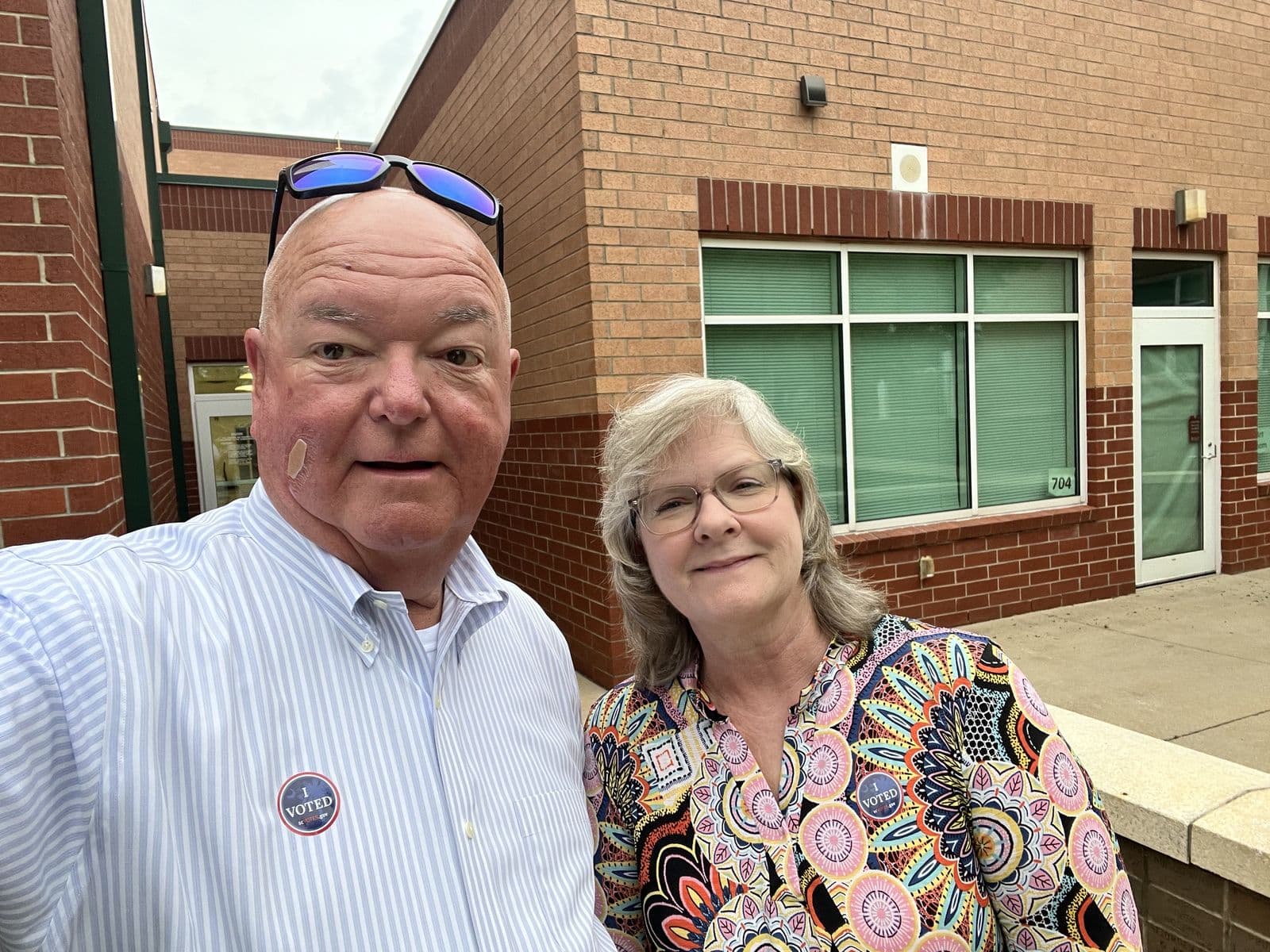 Chuck and Teresa Saylors outside a polling place wearing I Voted stickers.