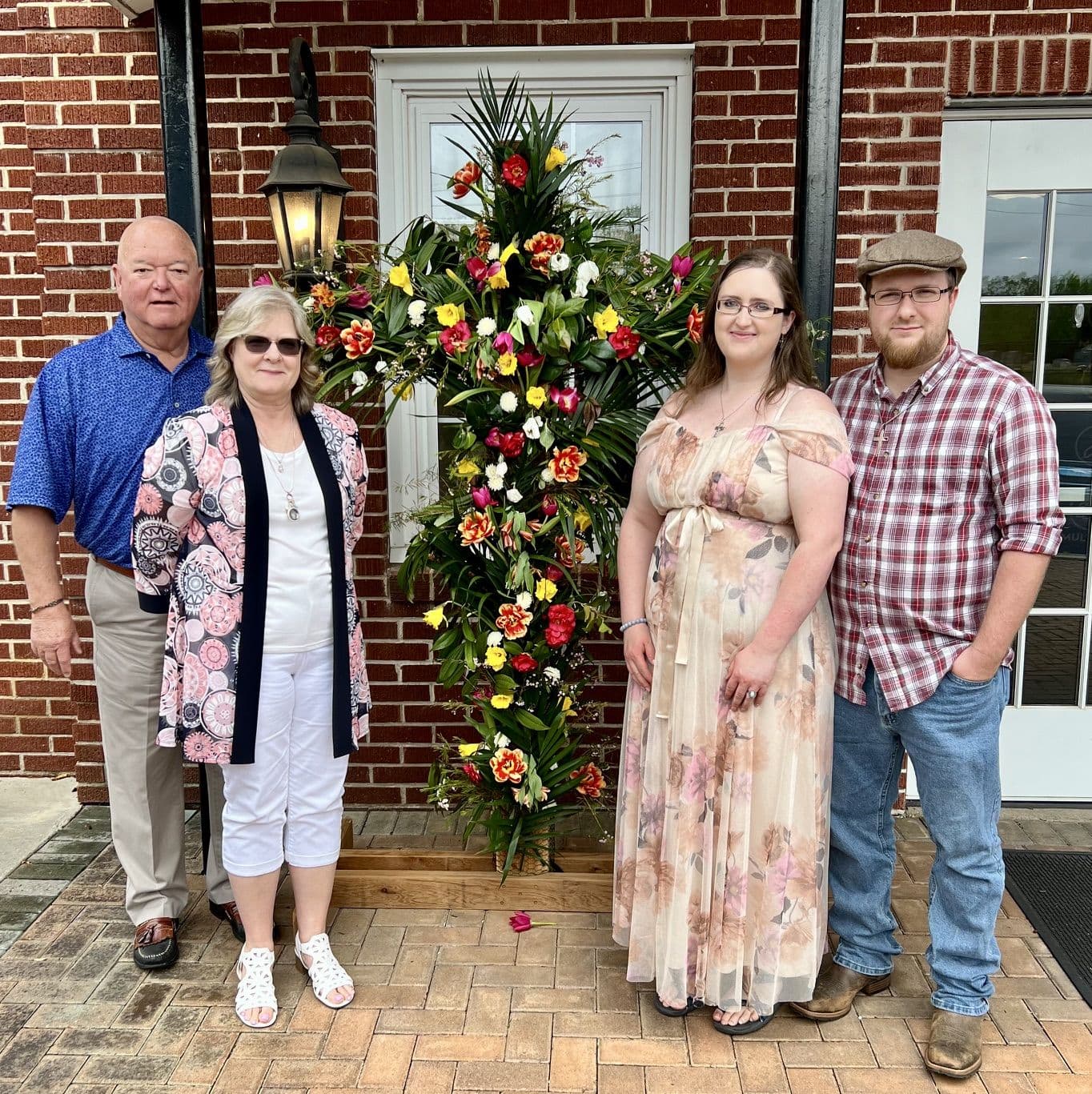Chuck and Teresa Saylors with family beside a flower-covered cross.